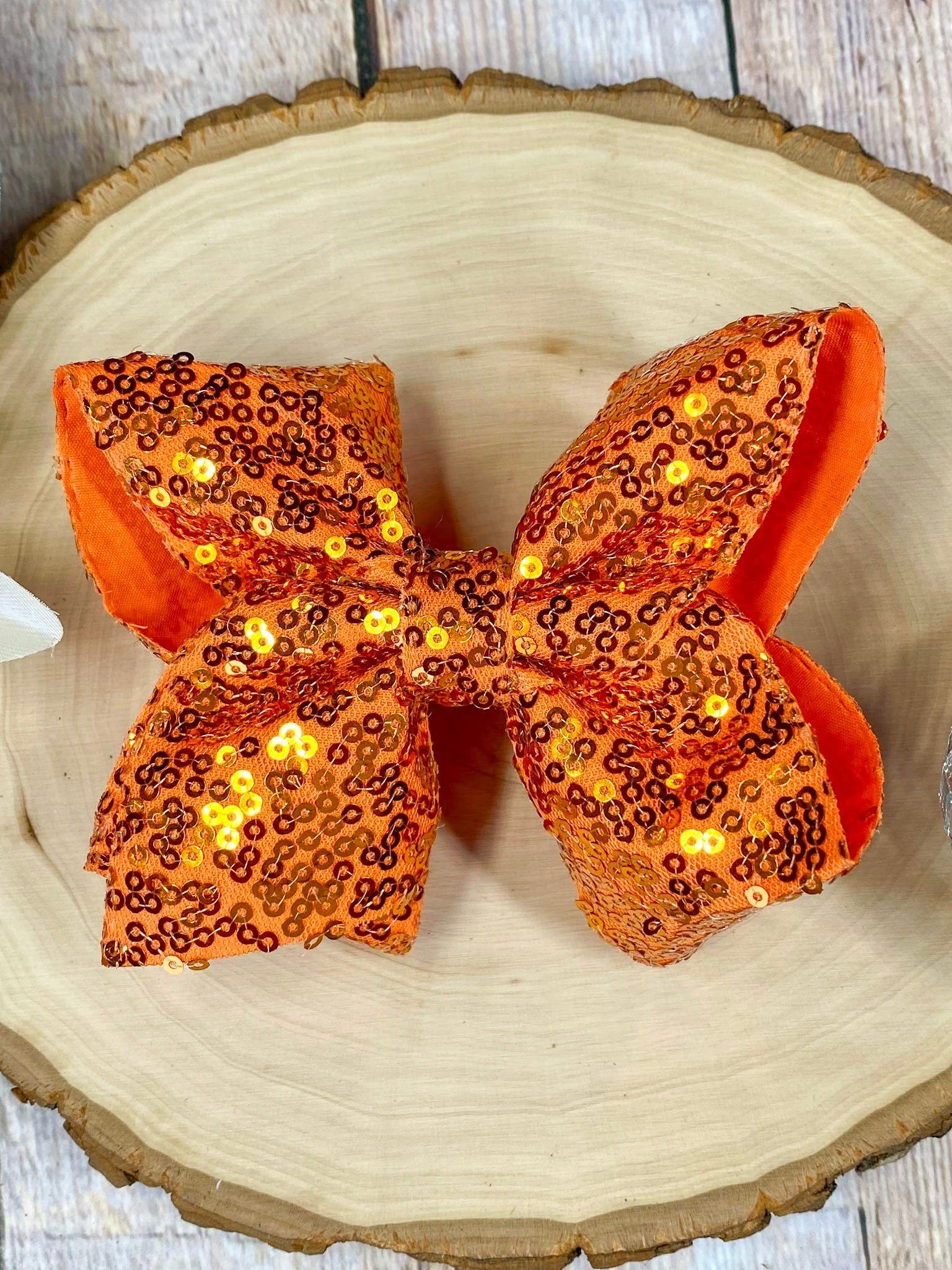 Orange sequin bow on a wooden surface