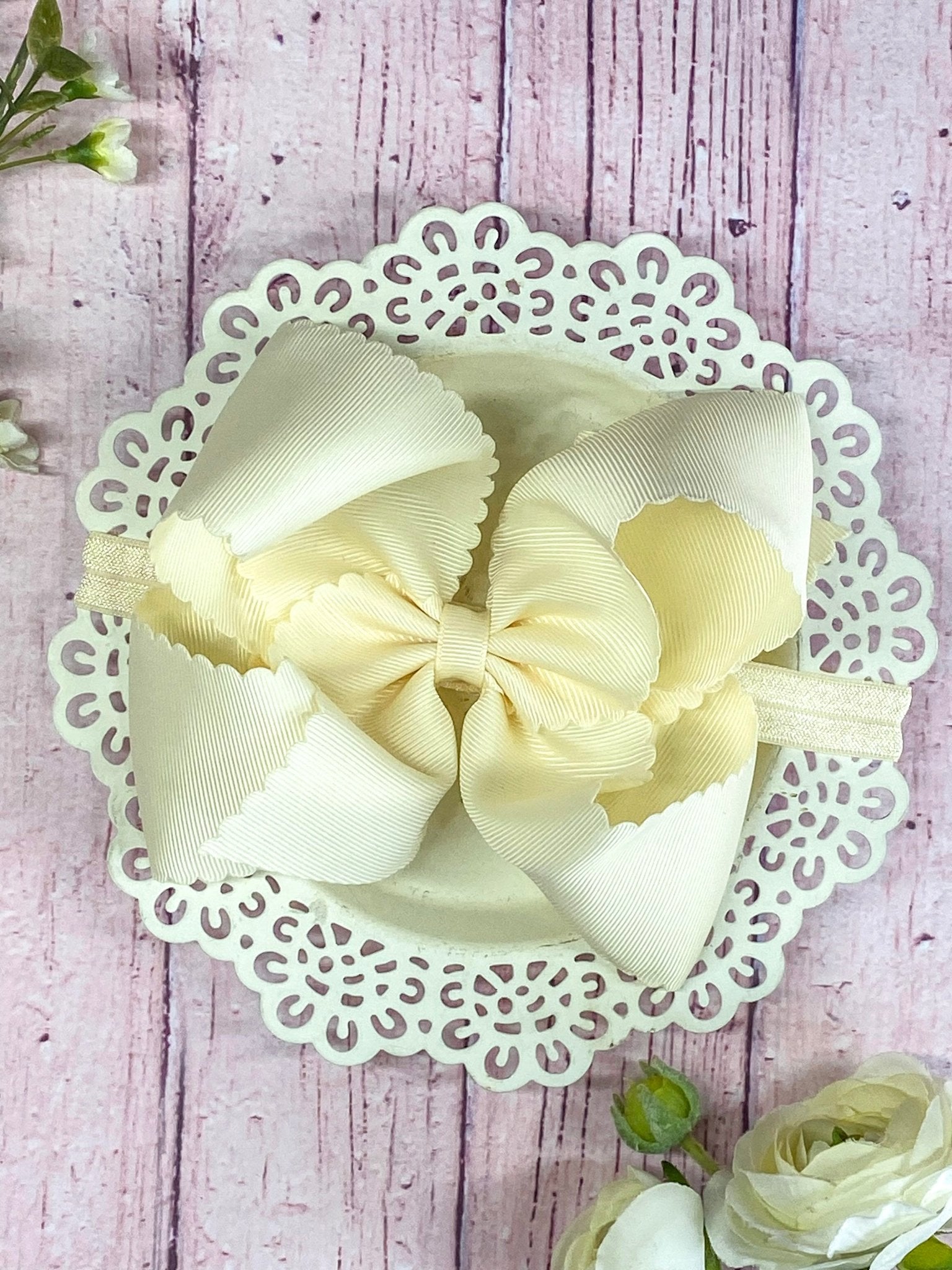 lvory hair bow on headband on wooden display