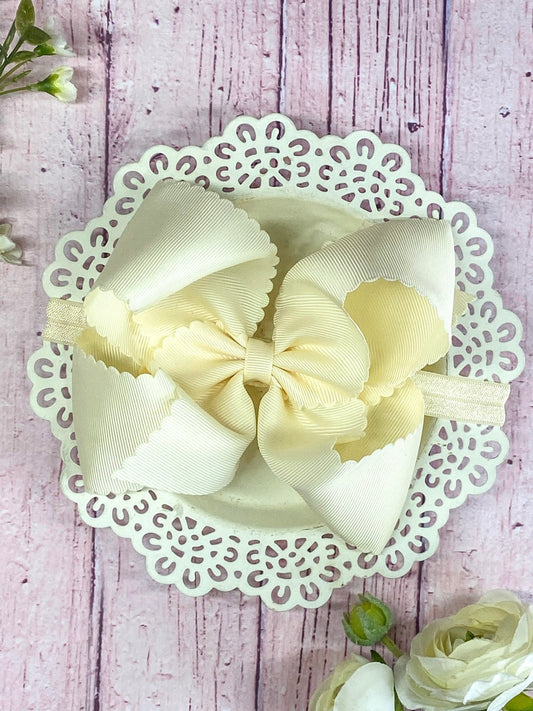 lvory hair bow on headband on wooden display