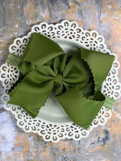 Olive Green bow headband on a decorative white plate with a textured background