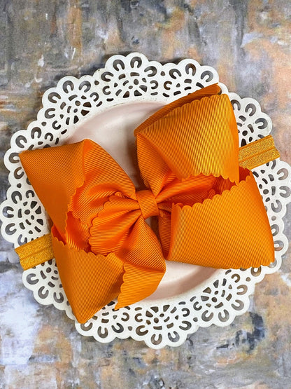 Orange hair bow headband on a decorative white plate with a textured background