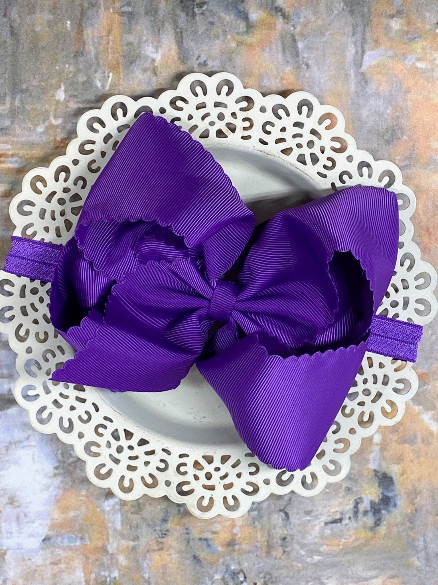 purple bow headband on a white doily with a textured background