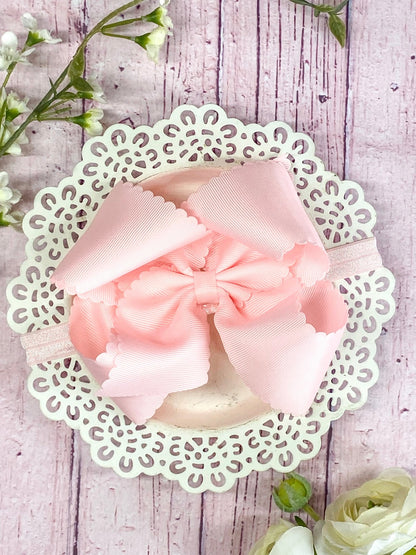 light pink hair bow on headband on wooden display