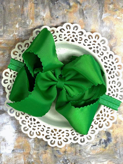 Green hair bow headband on a decorative white plate with a textured background