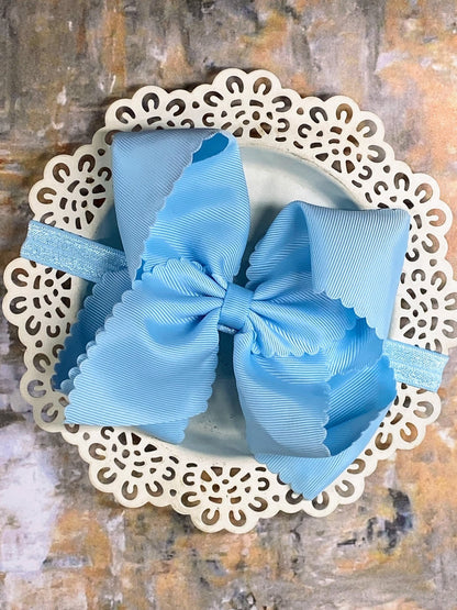 Large blue bow headband on a decorative white plate with a textured brown background