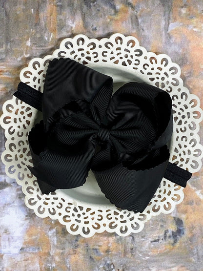 Black hair bow  headband on a white doily with a textured background