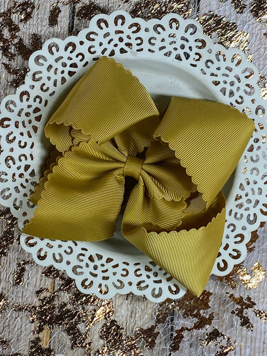 Yellow hair bow on a decorative white plate with a textured gold background