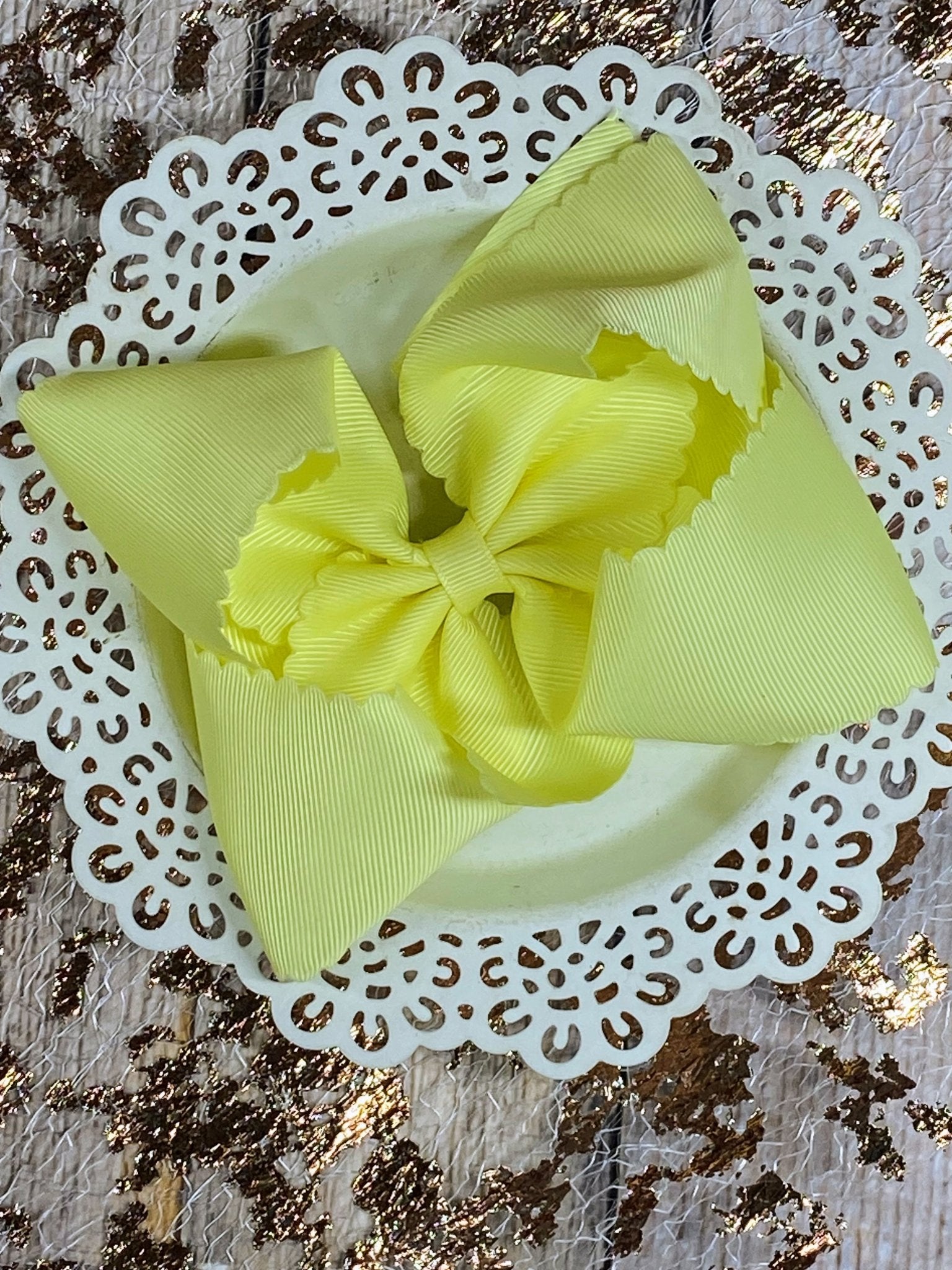 Yellow hair bow on a white doily with a textured background