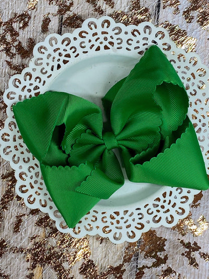 Green hair bow on a white doily with a gold leaf background
