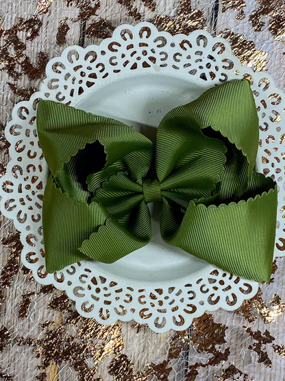 Green ribbon bow on a white doily with a textured gold background