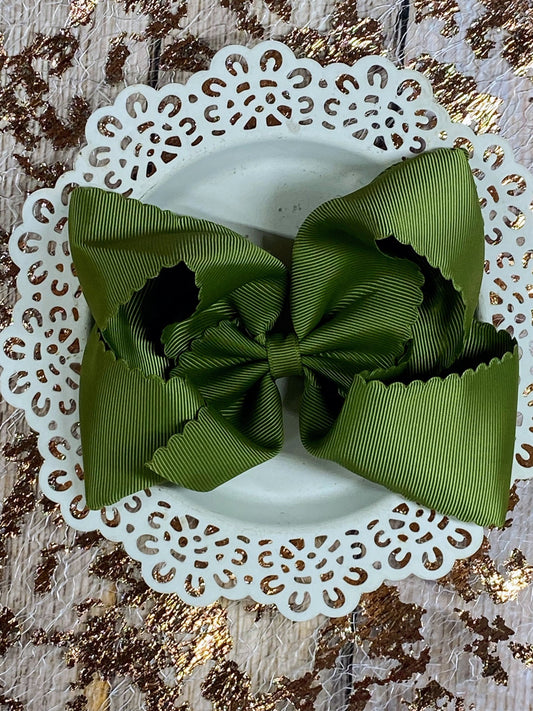 Green ribbon bow on a white doily with a textured gold background