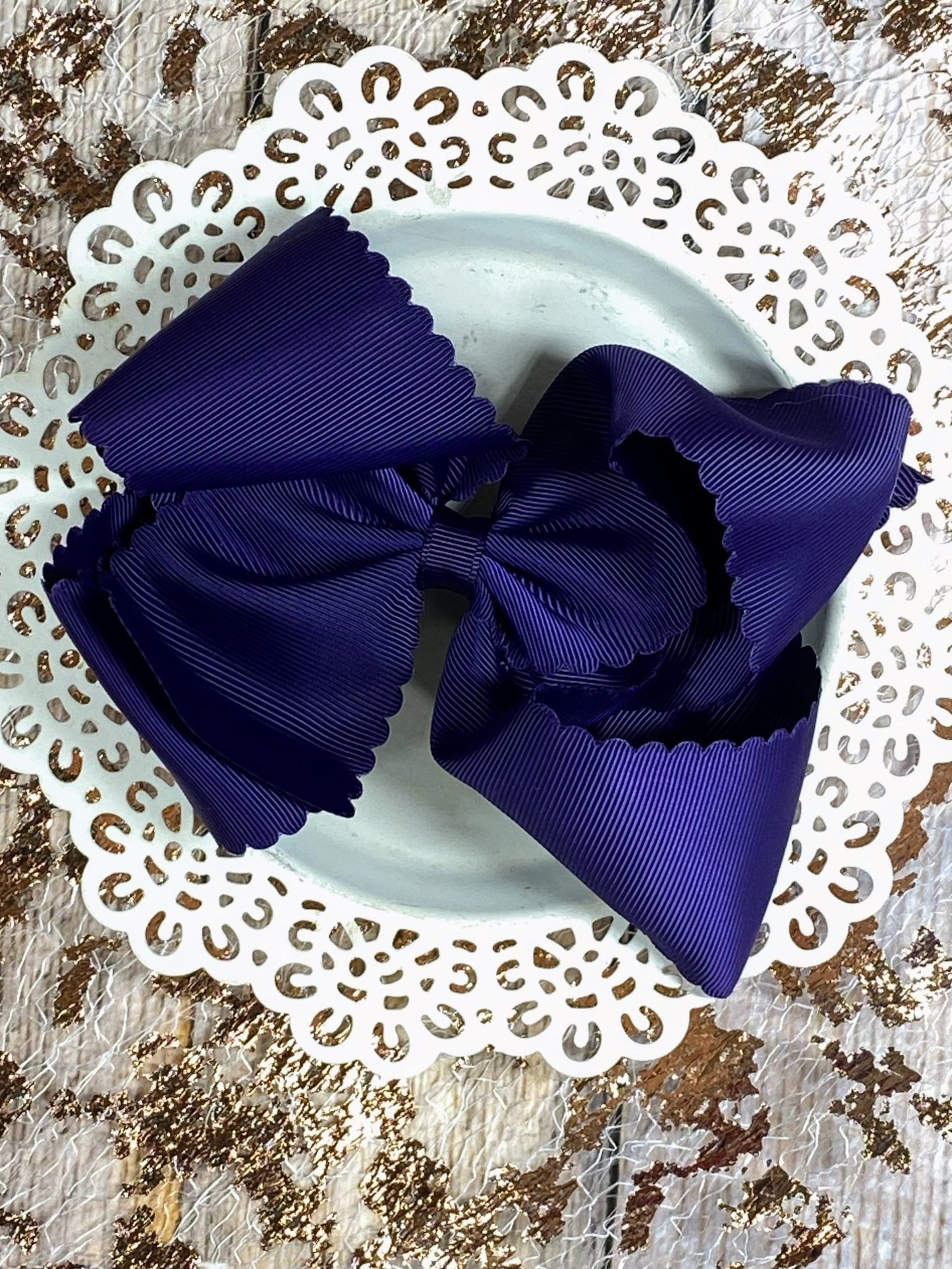 scalloped purple bow on a white doily with a textured brown background