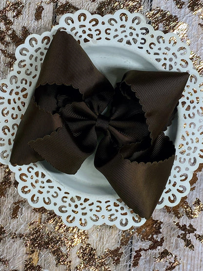 Brown hair bow on a decorative white plate with gold glitter background