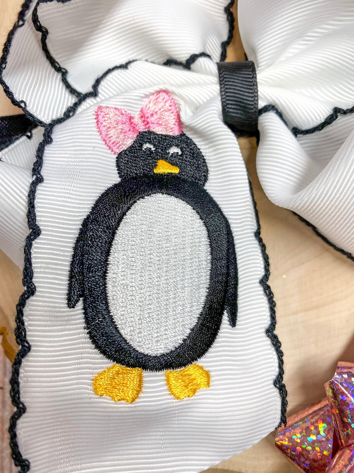 Close-up of penguin embroidery and moonstitch trim on bow headband