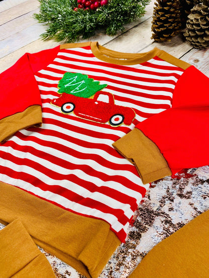 Close-up of boys’ holiday shirt with red truck carrying Christmas tree applique and red-and-white striped sleeves.