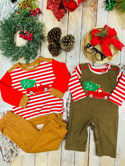 Flat lay of matching boys’ Christmas outfits with red truck and tree appliques both feature red and white stripes on top