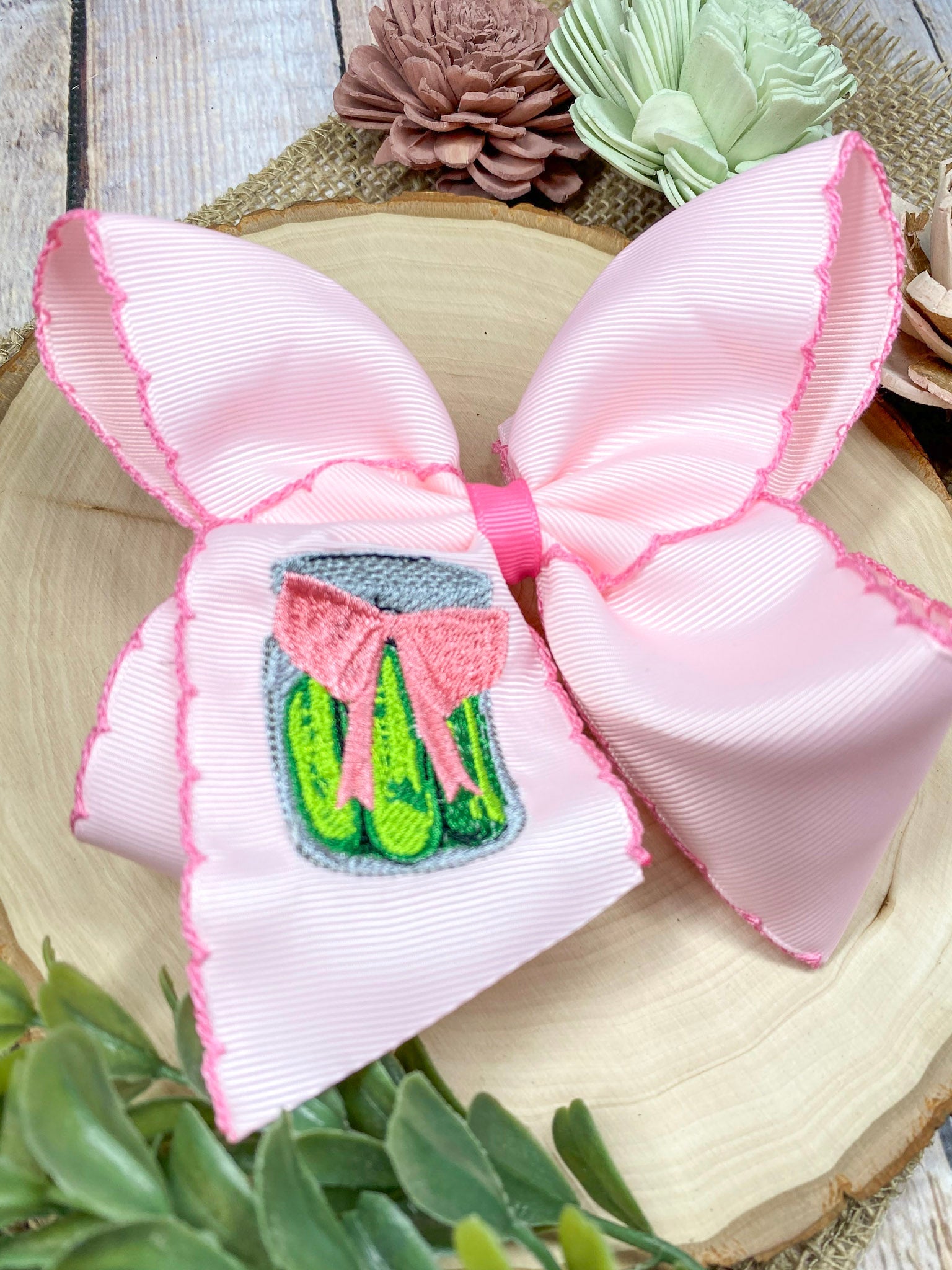 Pink Pickle Jar Moonstitch Hair Bow on a wooden background