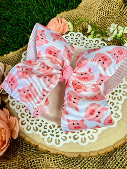 Large bow with pink pig pattern on a decorative surface with flowers and burlap.