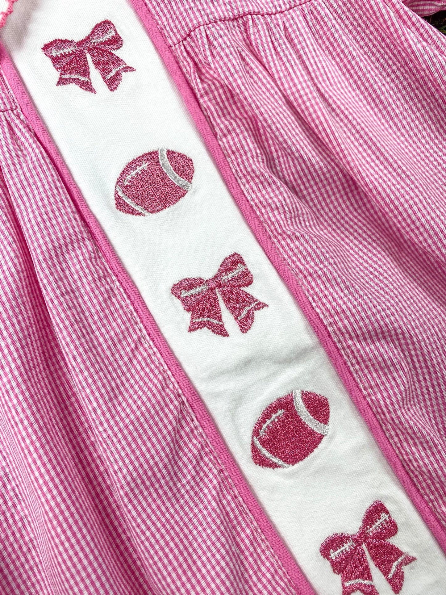 close up of the bows and football embroideries on front of the romper