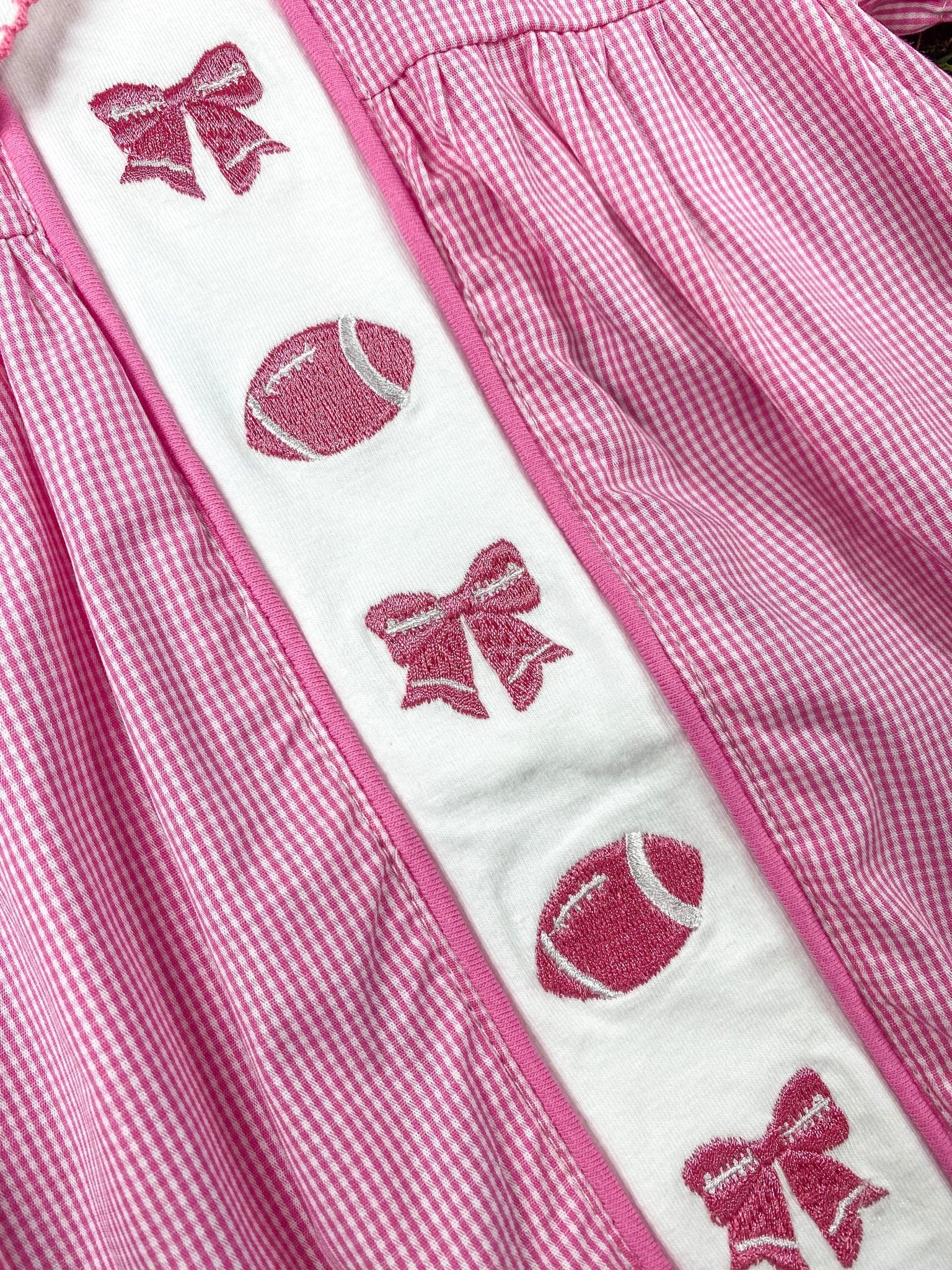 close up of the bows and football embroideries on front of the romper