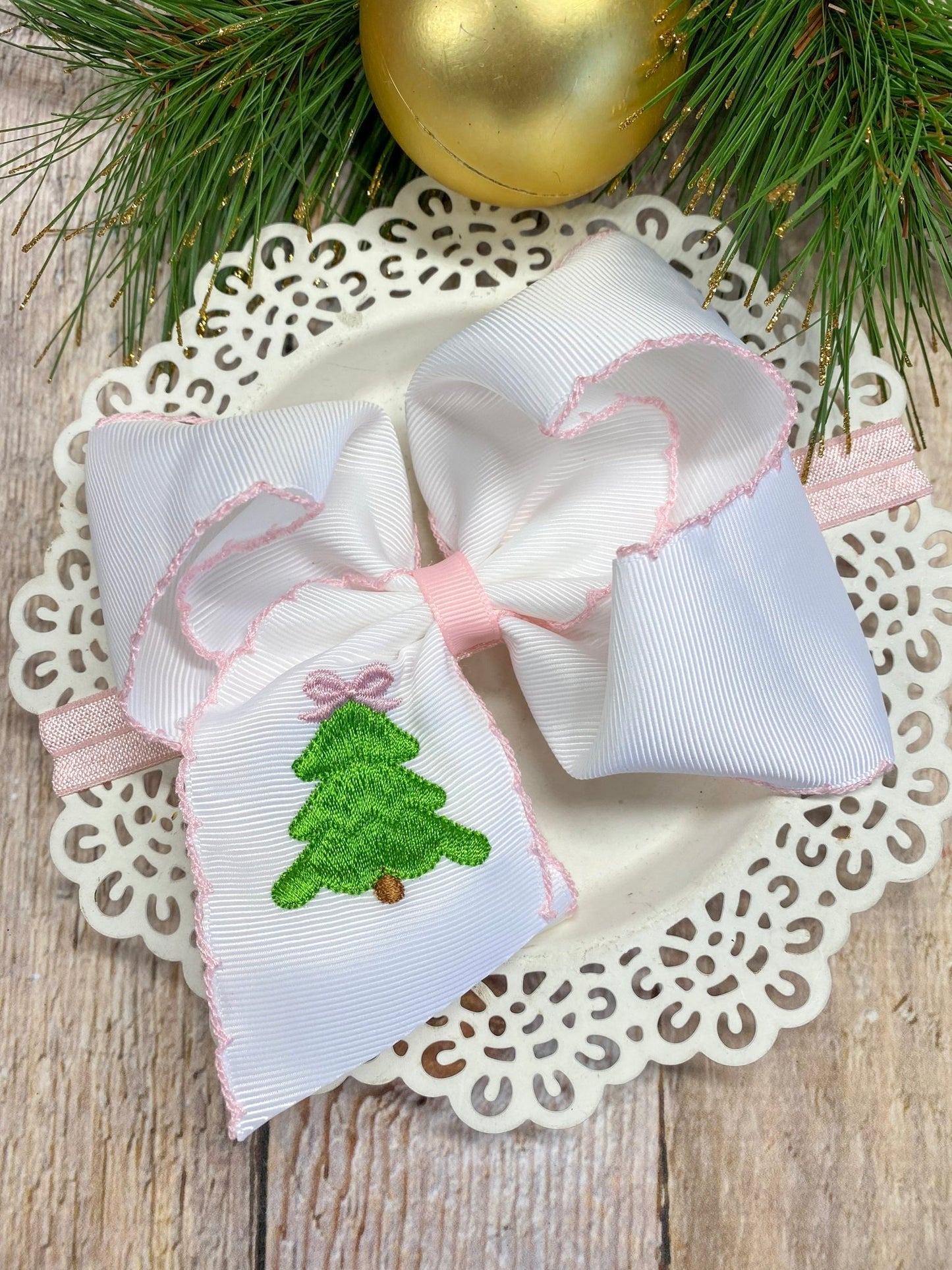 Pink Christmas Tree Embroidered Bow Headband on decorative plate with Christmas decorations