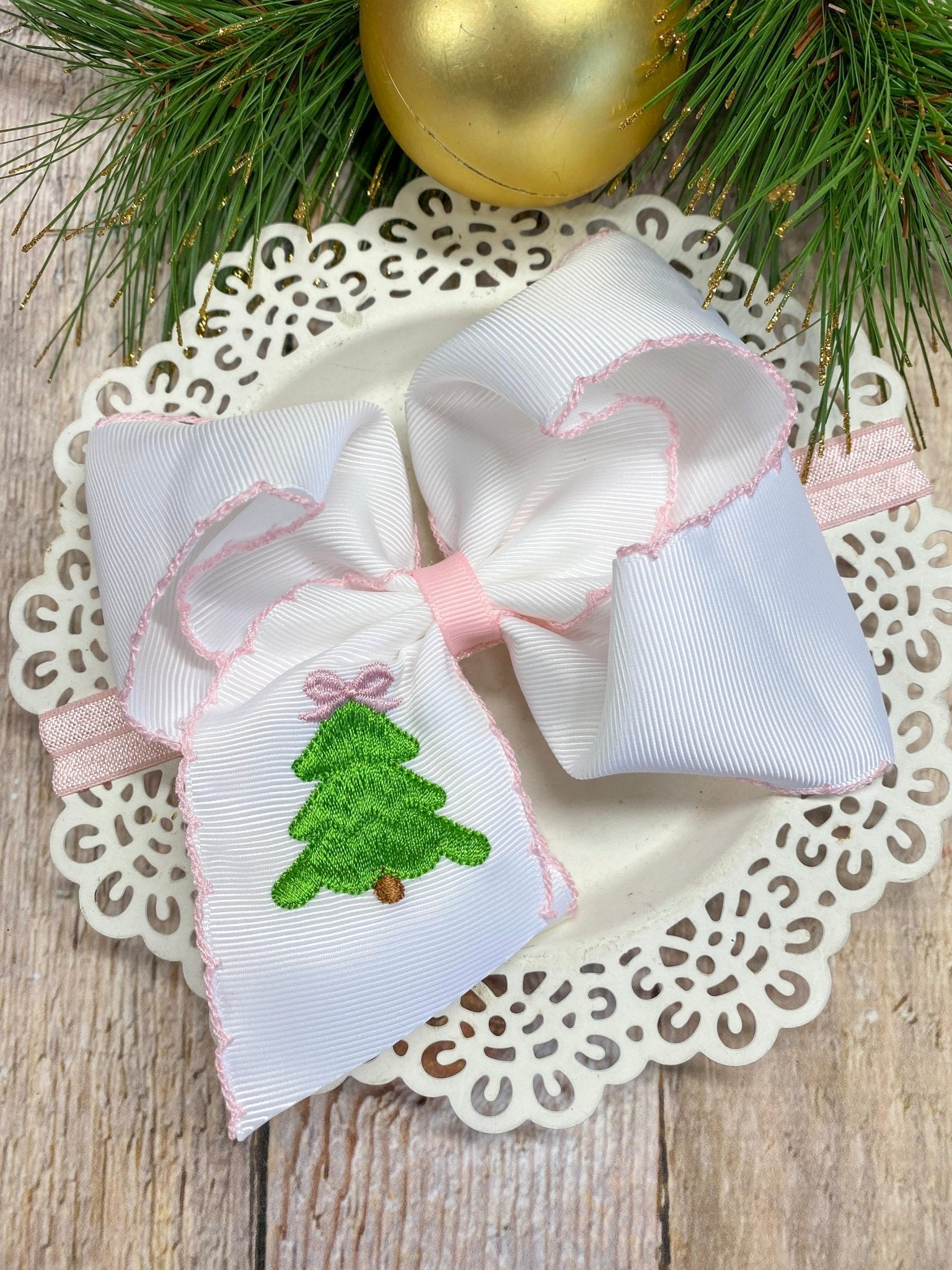 Pink Christmas Tree Embroidered Bow Headband on decorative plate with Christmas decorations
