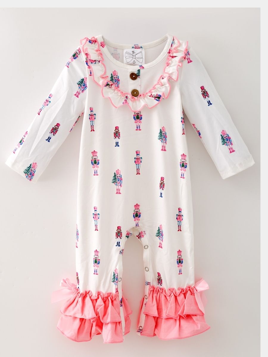 Pink Nutcracker Christmas infant romper with pastel nutcracker print, ruffle trim, pink bows, and snap closures.