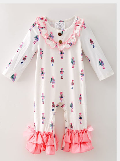 Pink Nutcracker Christmas infant romper with pastel nutcracker print, ruffle trim, pink bows, and snap closures.