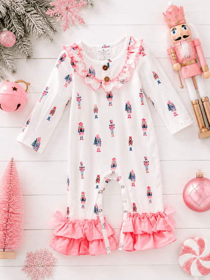 Pink Nutcracker Christmas infant romper featuring a pastel nutcracker print, ruffle trim, and festive holiday flatlay.