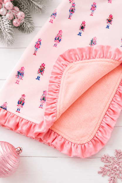 Pink Nutcracker Christmas ruffle minky baby blanket with pastel nutcracker print in a festive holiday flatlay.