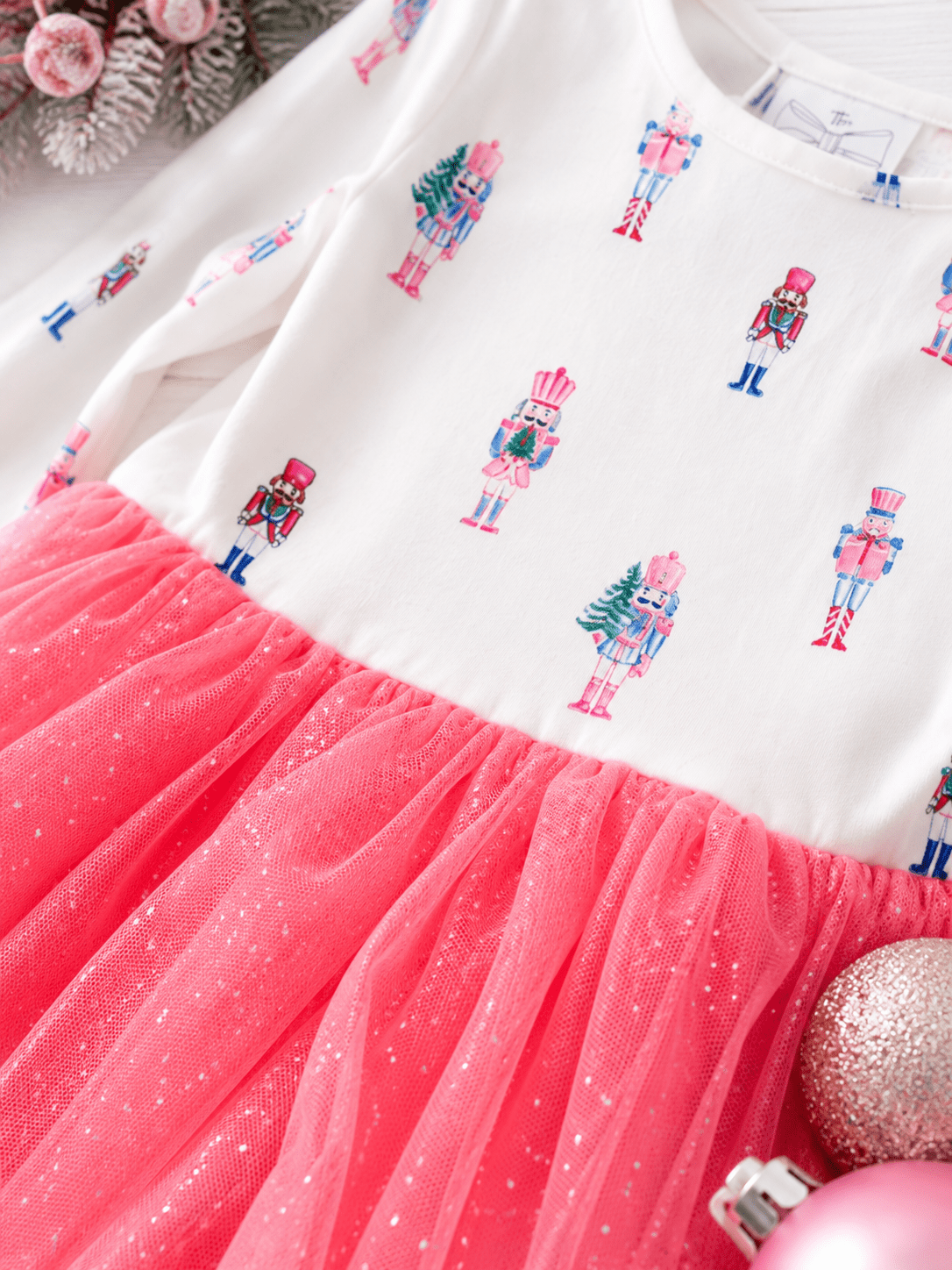 Close-up of the Pink Nutcracker Christmas tutu dress featuring pastel nutcracker print, glitter tulle skirt, and soft holiday fabric details for girls.