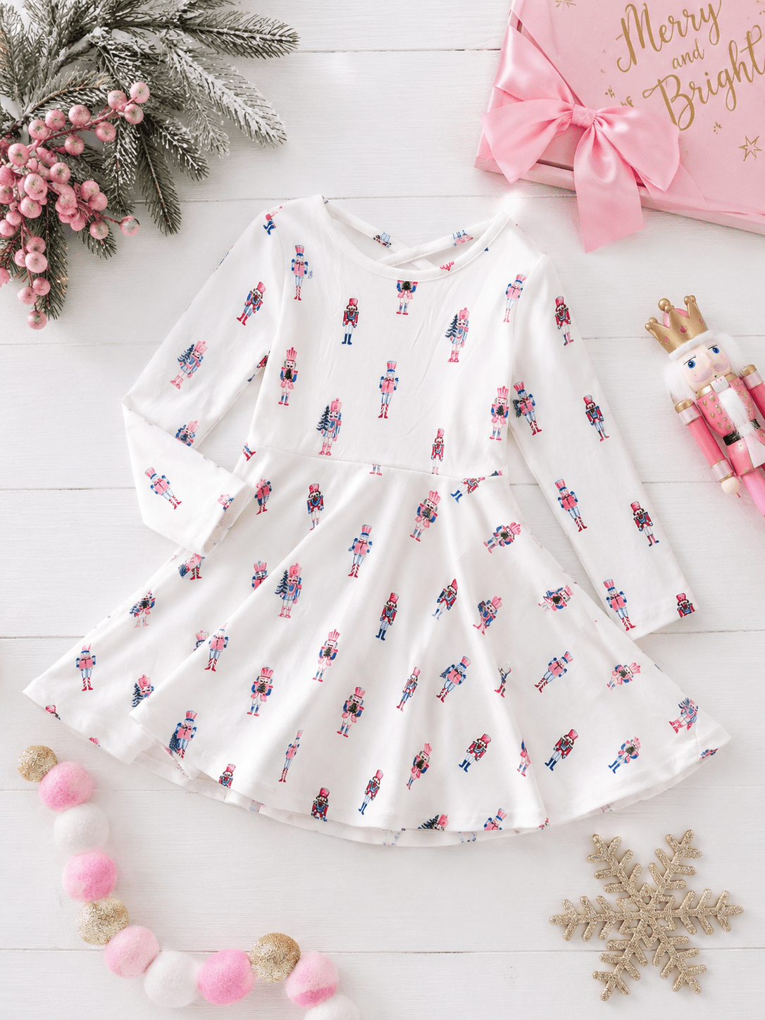 Pink Nutcracker Christmas twirl dress with pastel nutcracker print, long sleeves, and a full twirl skirt in a festive holiday flatlay.