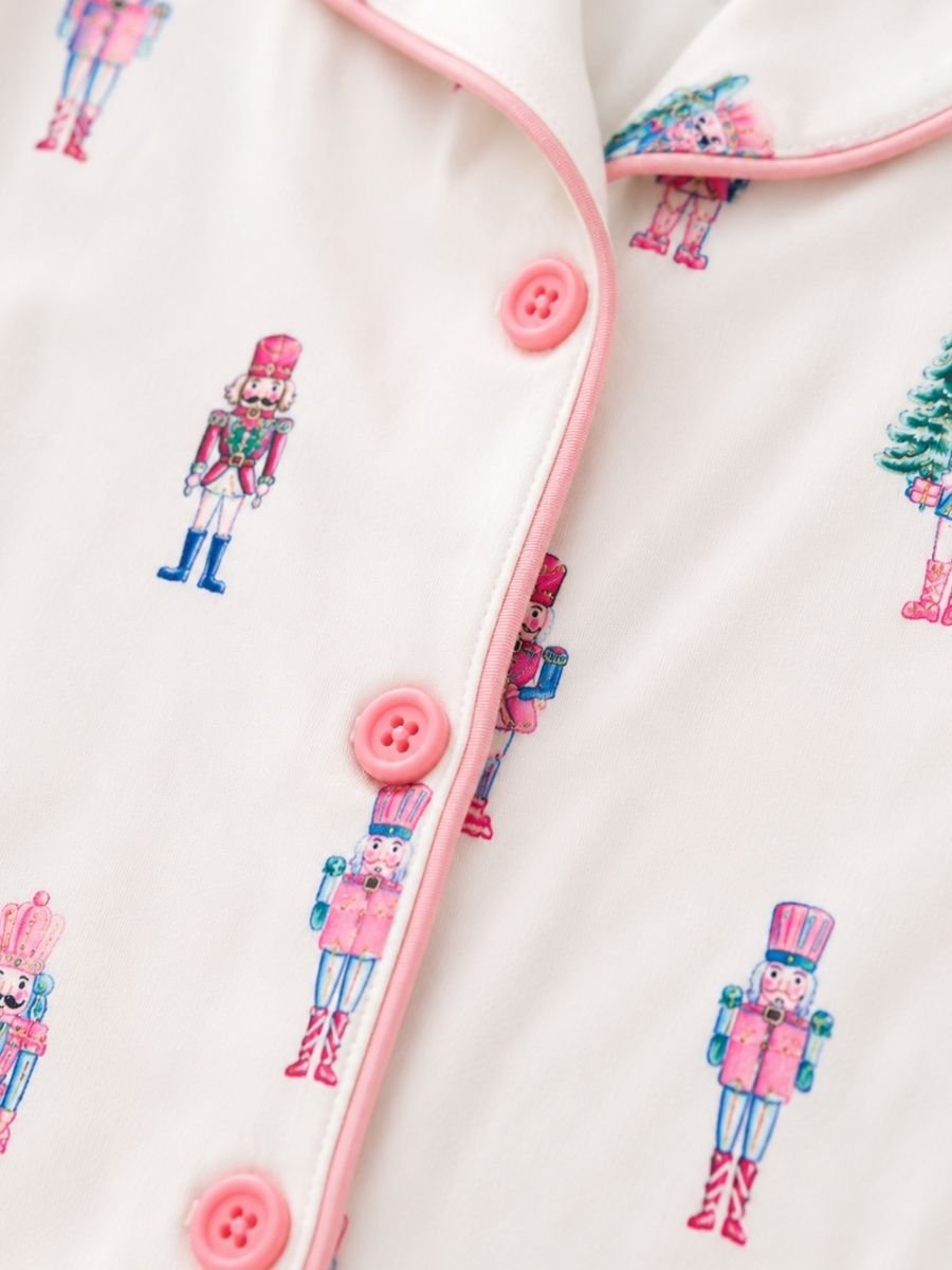 Close-up of Pink Nutcracker Christmas pajamas with pastel nutcracker print, pink piping, and button-front detail.