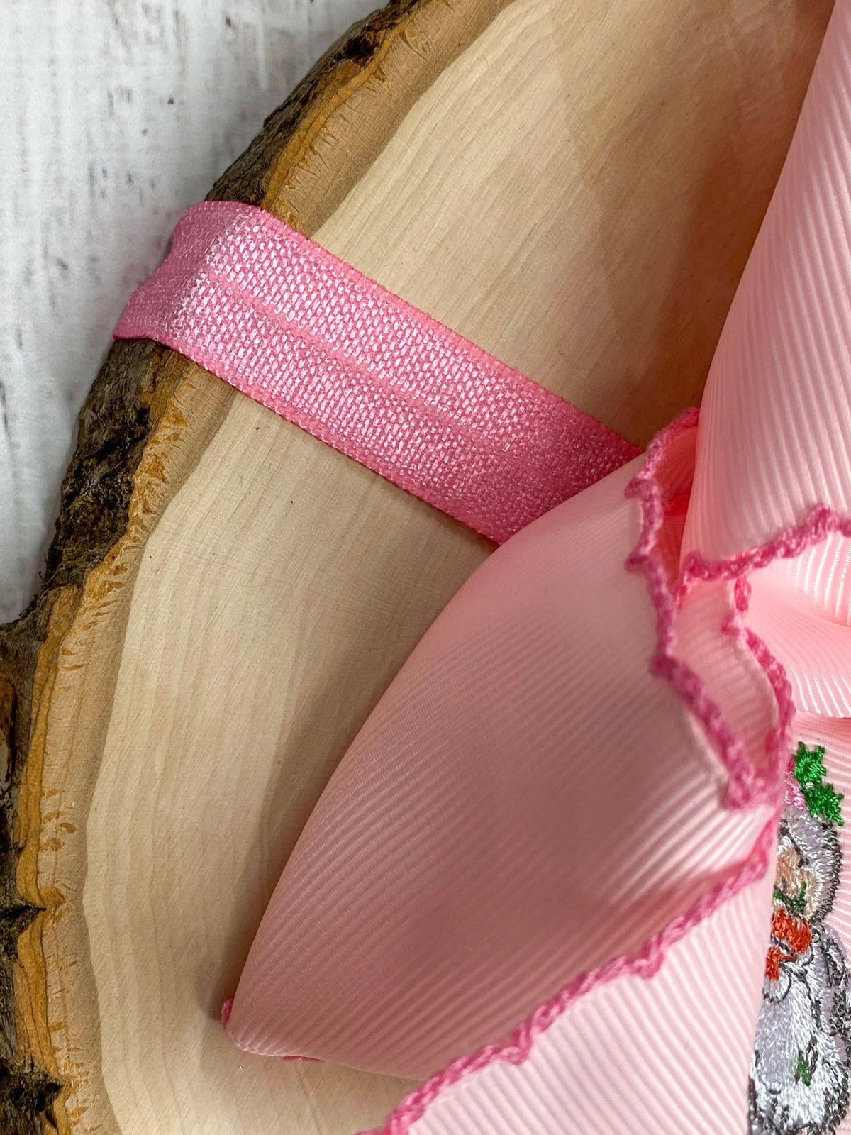 Back of pink Santa embroidered bow headband showing satin elastic band