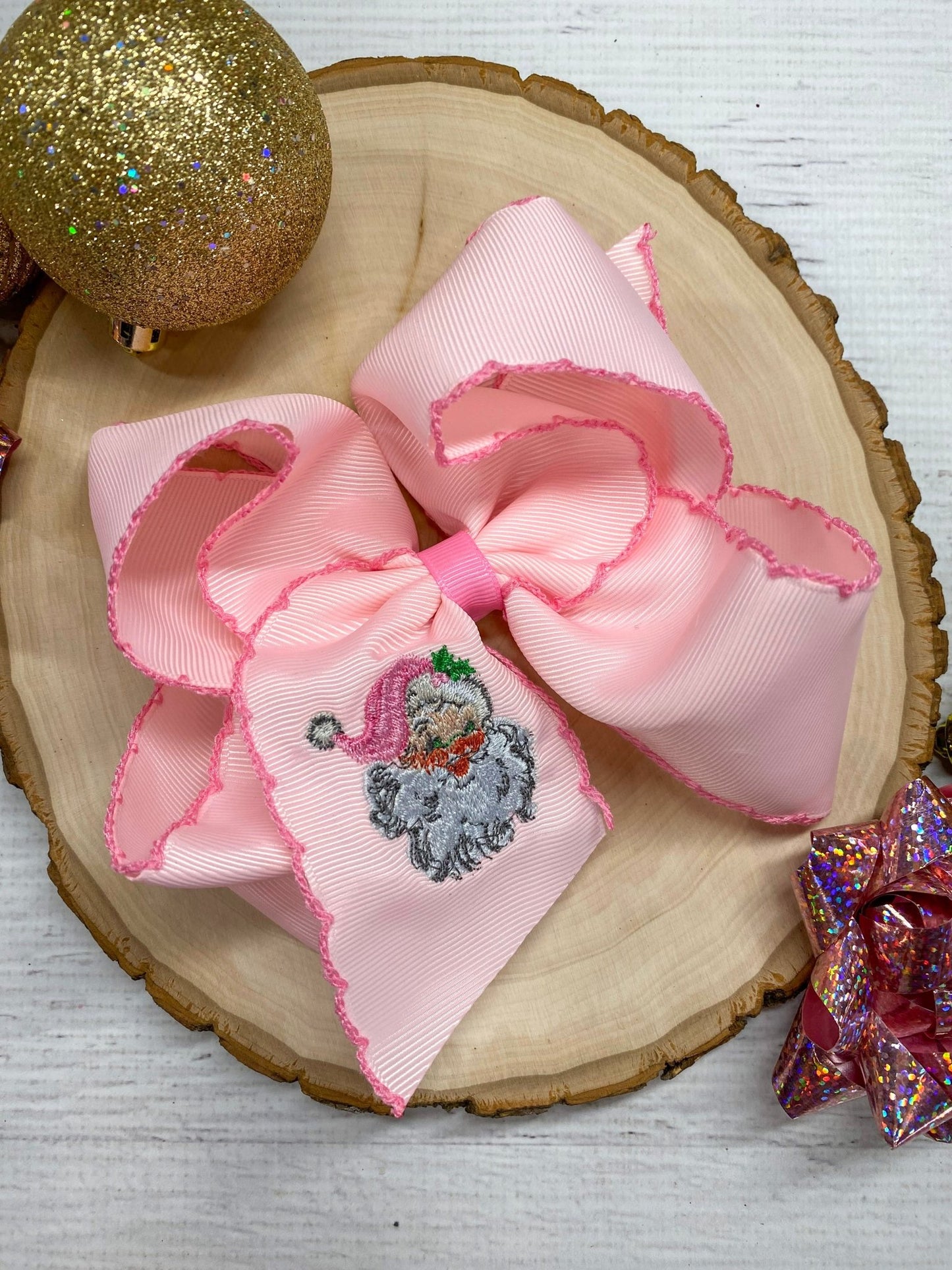 Pink Santa Embroidered Hair Bow - Clip Style on wooden surface