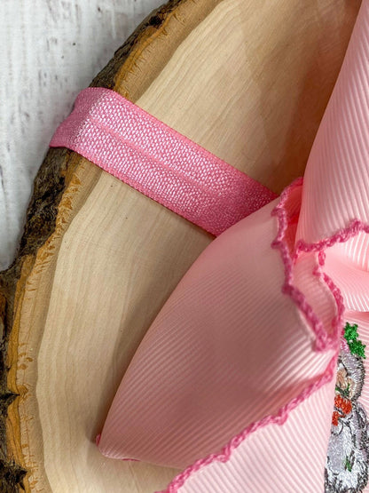 Close-up of pink Santa bow headband showing satin elastic band