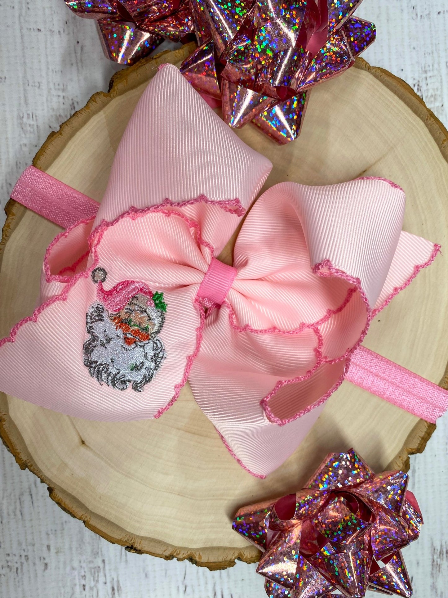 Pink Santa Embroidered Bow Headband on wooden surface