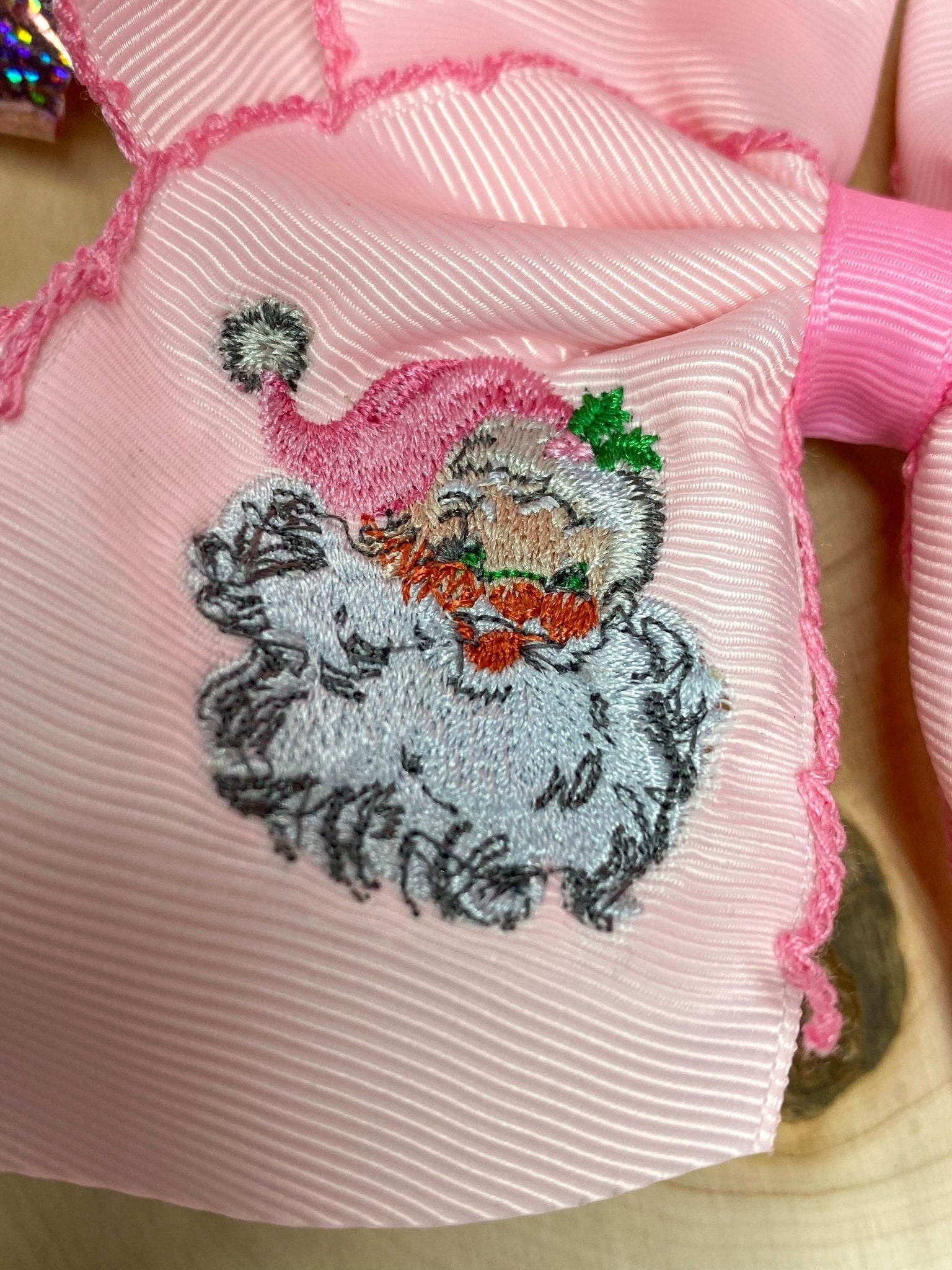 Close-up of Santa face embroidery on pink hair bow fabric