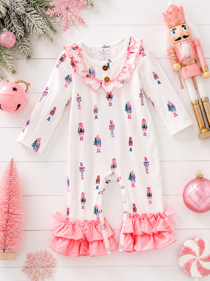 Pink Nutcracker Christmas infant romper featuring a pastel nutcracker print, ruffle trim, and festive holiday flatlay.