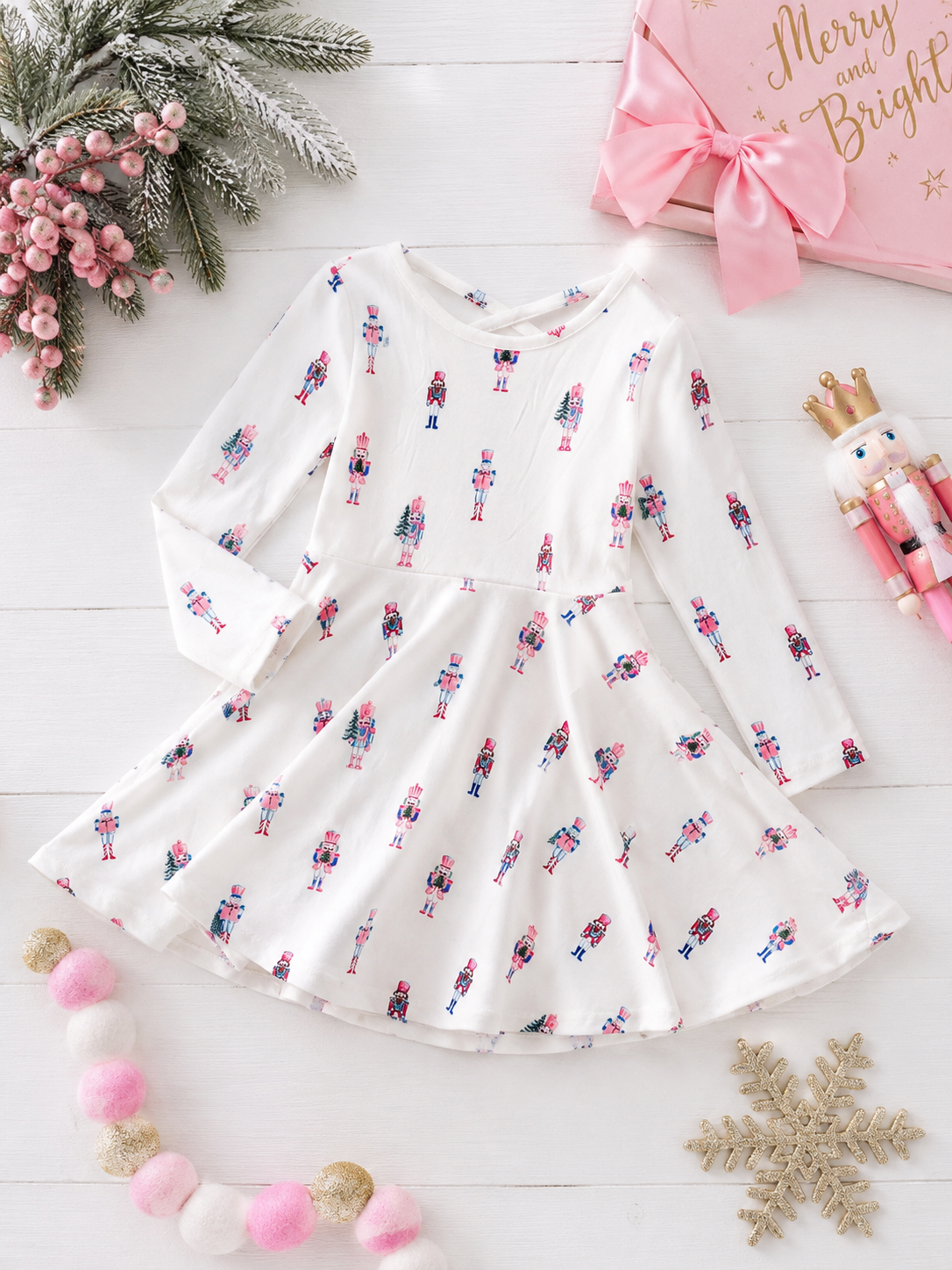 Pink Nutcracker Christmas twirl dress with pastel nutcracker print, long sleeves, and a full twirl skirt in a festive holiday flatlay.