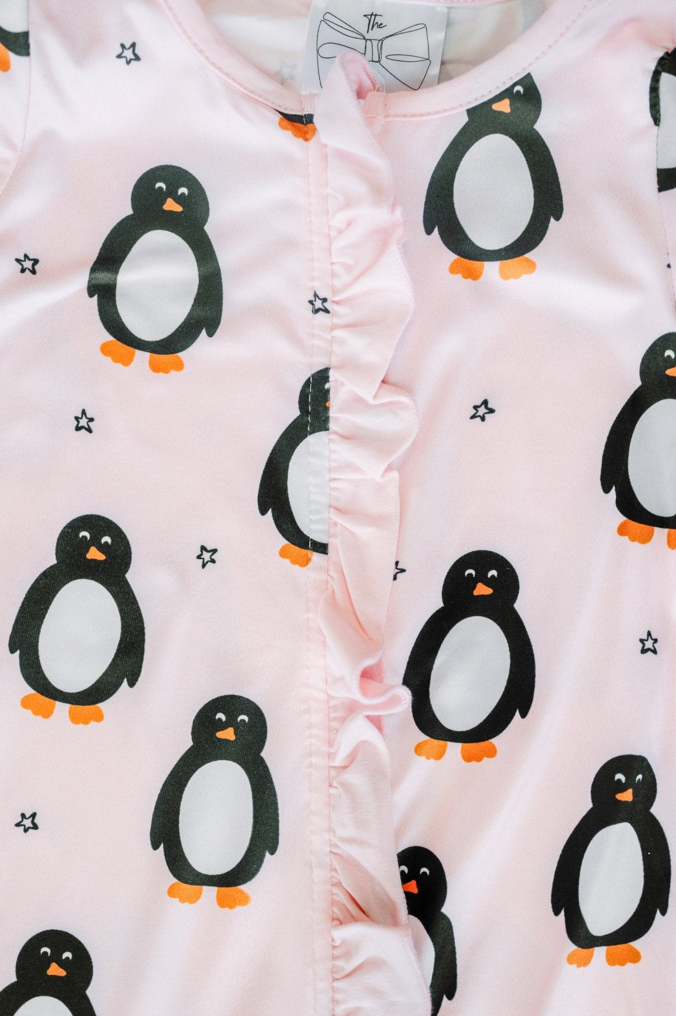 Baby romper with penguin pattern on a light pink background
