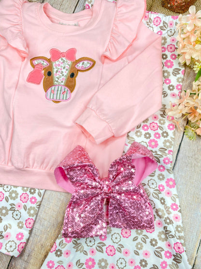 girls western two-piece with cow appliqué ruffle sweatshirt and pink floral bell bottoms on a wooden background