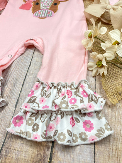 baby girl western one-piece with floral cow appliqué and layered floral ruffle leg hems on a wooden background