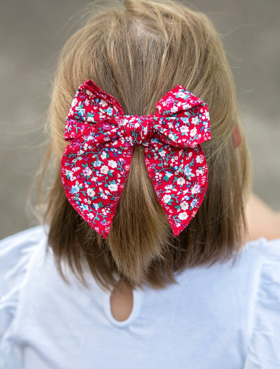 Girl wearing a red floral hand tied hair bow