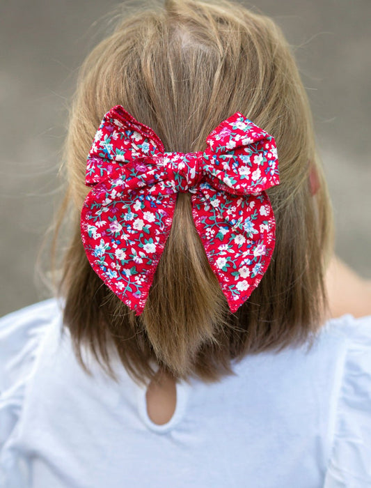 Girl wearing a red floral hand tied hair bow