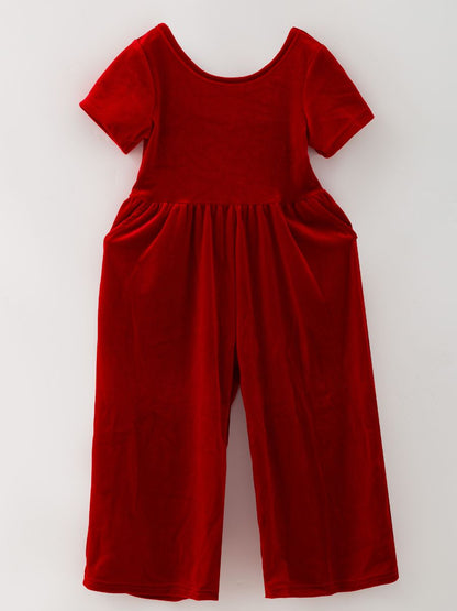 Red girls’ velvet holiday jumpsuit with wide legs, short sleeves and side pockets.