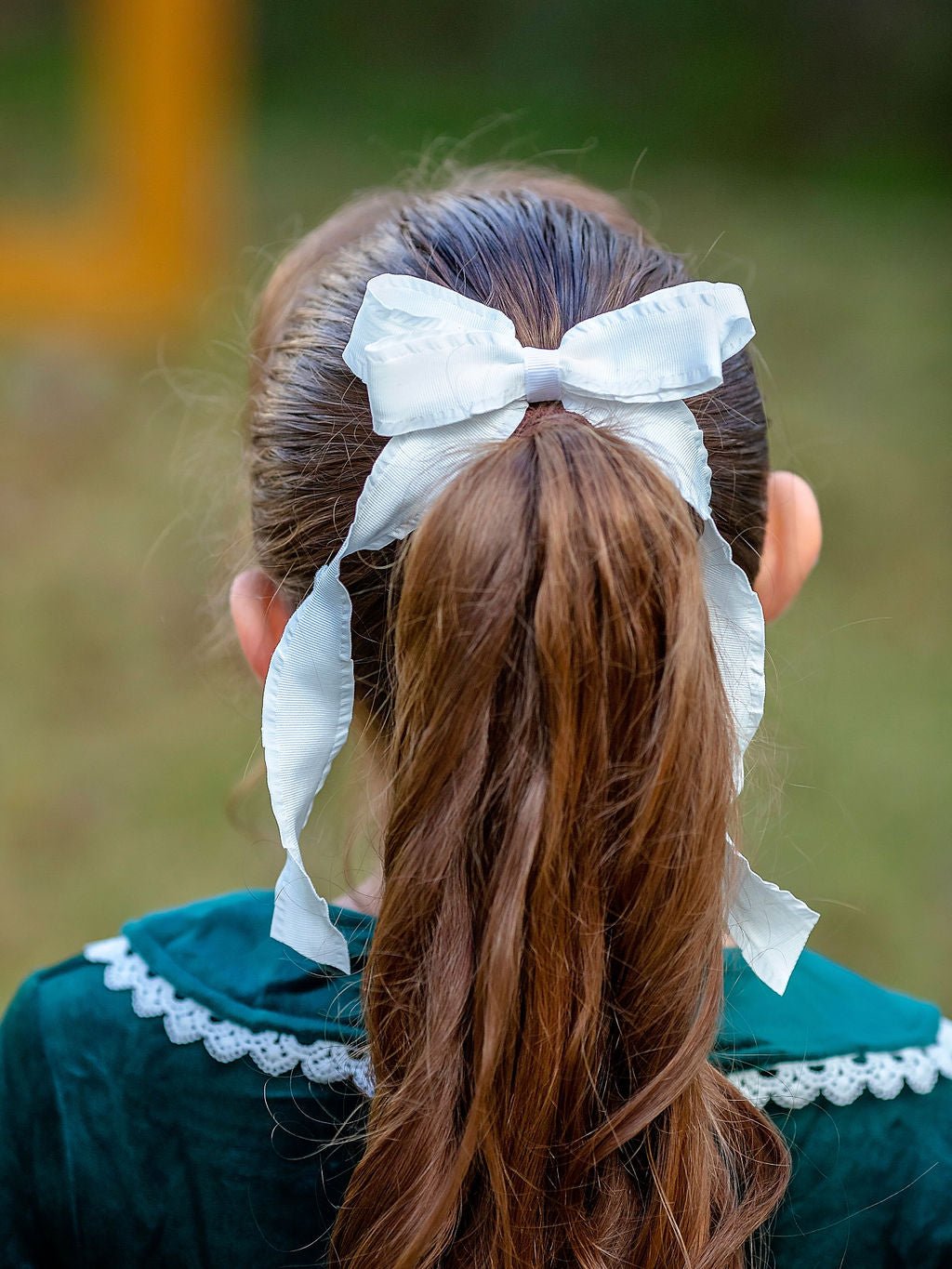 Girl wearing a white ruffle edge ribbon hair bow