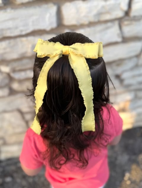 Girl wearing a yellow ruffle edge ribbon hair bow