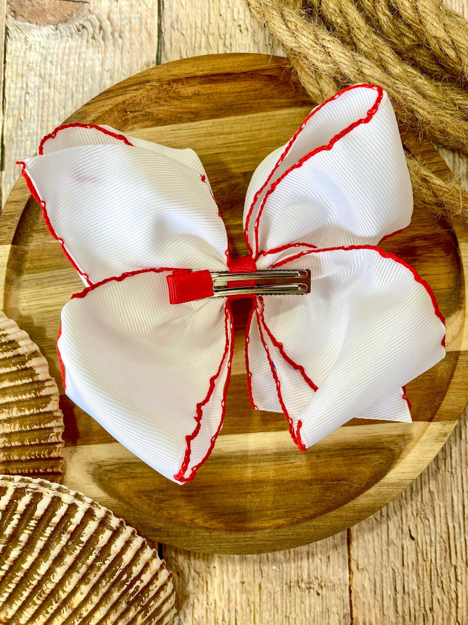 white hairbow with red trim on a wooden surface