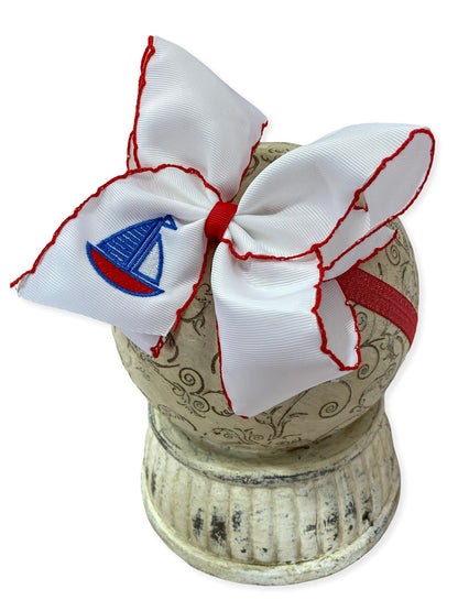 white headband with red trim and embroidered sailboat on a white background